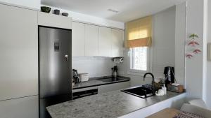 a kitchen with white cabinets and a black refrigerator at Apartamento con parking en Torre Almenara in Punta Umbría +14 photos