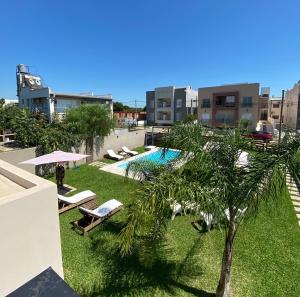 a pool with lounge chairs and a palm tree on a building at Maderos Apart in Federación
