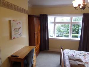 a bedroom with a table and a window and a bed at Designer Cottage in Christchurch
