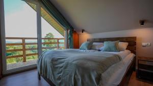 a bedroom with a large bed with a large window at Domek na Modyni, Dwa domki z ruską balią i sauną in Łącko
