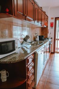 a kitchen with a sink and a microwave at Férias em Cerveira in Vila Nova de Cerveira