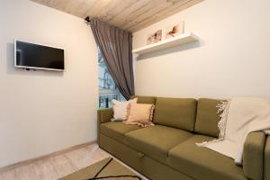 ein Wohnzimmer mit einem grünen Sofa und einem Flachbildfernseher in der Unterkunft Pajūrio namelis FAMILY BEACH HOUSE su baseinu in Palanga
