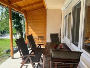 a porch with chairs and a wooden table on a patio at Jó hely in Balatonalmádi
