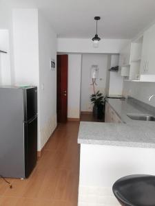 eine Küche mit einem schwarzen Kühlschrank und Holzböden in der Unterkunft Las cumbres del mirador in La Libertad