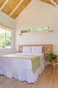 a bedroom with a large white bed with a window at Cedrela Beach Villas in Uvita