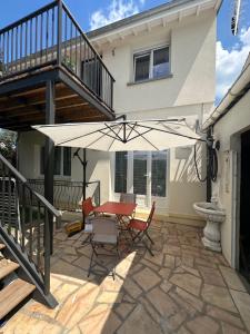 a patio with a table and chairs and an umbrella at Maison cosy climatisée avec jardin in Aulnay-sous-Bois