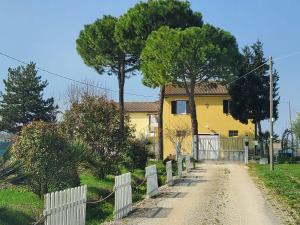 a yellow house with a fence next to a dirt road at CaSAle in Castelfidardo