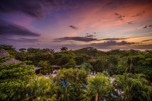 a view of a resort with trees and a sunset at Cala Luna Boutique Hotel & Villas in Tamarindo