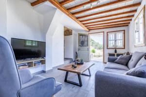 a living room with a couch and a tv and a table at Solea Cottage - Bright Escape in Skopelos in Skopelos Town