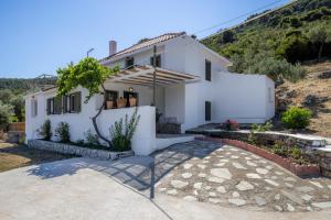 a white house with a hill in the background at Solea Cottage - Bright Escape in Skopelos in Skopelos Town