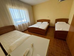 two beds in a small room with a window at Ari's Guest House in Borsh