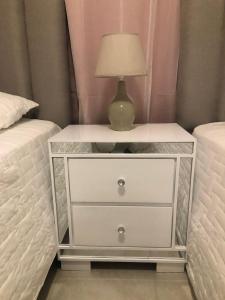 a white nightstand with a lamp on it next to two beds at santiago de los caballeros hipanoamericana in Santiago de los Caballeros +18 photos