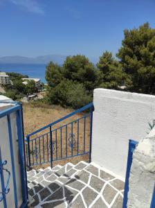 a staircase with a blue gate with the ocean in the background at Θέα από ψηλά in Áyioi Apóstoloi