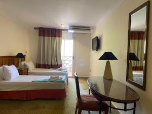 a room with two beds and a table and a mirror at Bianchi Hotel in Alexandria