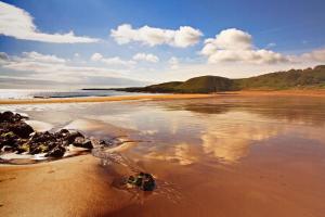 a beach with a reflection of the sky in the water at The Smugglers in Eyemouth