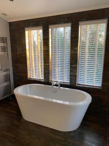 a large white bath tub in a room with windows at The Smugglers in Eyemouth +3 photos