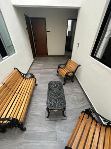two benches sitting in a hallway next to a door at El salto de Camela Hostal in Uruapan del Progreso +6 photos