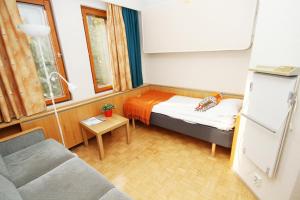 ein kleines Zimmer mit einem Bett und einer Couch in der Unterkunft Aapiskukko Hotel in Pälkäne