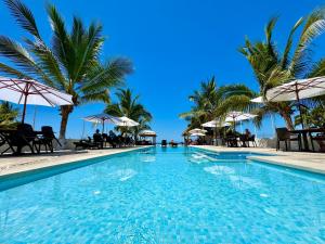 a swimming pool with palm trees and umbrellas at Kavalá in San Blas