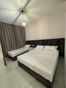two beds in a hotel room with white sheets at AJ Apartments in Orikum