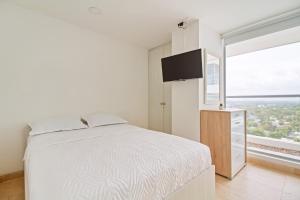 Un dormitorio blanco con una cama y una ventana grande. en Sensacional! Apartamento Cartagena Morros Sonesta, en Cartagena de Indias