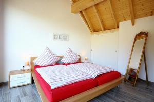 a bedroom with a red bed and a mirror at Alte Scheune Bruns in Lehmen