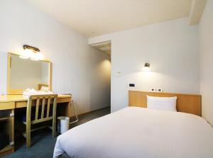a room with a bed and a desk and a mirror at Island Hotel in Nagano