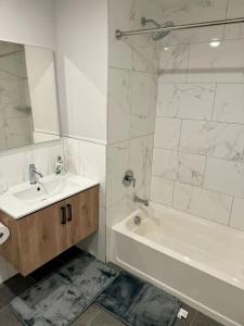 un bagno bianco con lavandino, vasca e specchio di Luxury Stay for NYC visit Jersey City 7 Min Walk NYC Train Station a Jersey City
