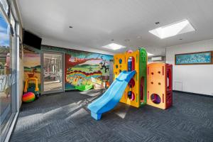 ein Kinderspielzimmer mit einer Rutsche und einem Wandbild in der Unterkunft Tasman Holiday Parks - Waihi Beach in Waihi Beach