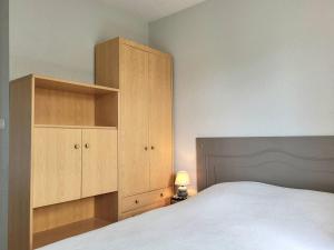 a bedroom with a bed and a large wooden cabinet at Charmant T2 à 300m de la plage en Normandie – Balcon, parking et local vélo inclus - FR-1-788-21 in Varaville