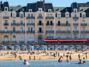 a group of people on the beach in front of a building at Charmant T2 à 300m de la plage en Normandie – Balcon, parking et local vélo inclus - FR-1-788-21 in Varaville