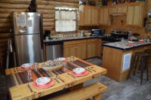 Una cocina con una mesa y un refrigerador de acero inoxidable. en Hidden Valley Heaven - WiFi - Satellite - Washer - Dryer - Wood Stove - Semi-Secluded - Quiet Neighborhood - Beautiful Views, en Red River