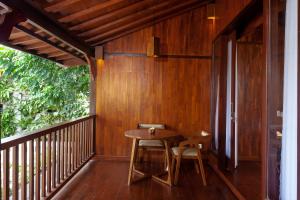 a wooden porch with a table and chairs on a balcony at Manah Shanti Suites by Pramana Villas in Ubud