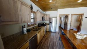 a kitchen with wooden cabinets and a refrigerator at Lost in Paradise - Pet Friendly - Hot Tub - WiFi - Fireplace - Grill - On the River - Fire Pit in Red River