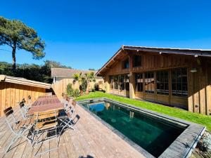 a house with a pool and a table and chairs at La Villa Les Inséparables in Lège-Cap-Ferret