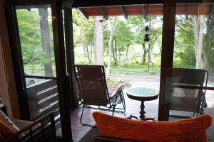 eine abgeschirmte Veranda mit einem Tisch und Stühlen in der Unterkunft Pond Cabin Myoko in Myōkō