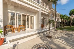 a white house with chairs and a table on the porch at Kembang Kuning in Uluwatu