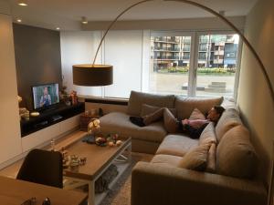 Eine Frau, die auf einer Couch im Wohnzimmer liegt in der Unterkunft Studio Appartement Van Bunnenplein in Knokke-Heist