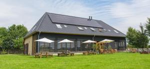 een gebouw met tafels en parasols in het gras bij B&B de Luijenbergh in Oud-Gastel