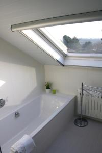 eine weiße Badewanne im Bad mit Fenster in der Unterkunft B&B Le Jardin d'Epicure in Olne