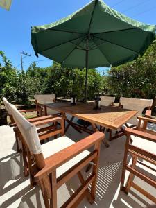 a picnic table with a green umbrella and chairs at Melina house in Ayiá