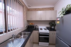 a kitchen with white cabinets and a sink and a refrigerator at 52 on Mort in Lithgow +3 photos