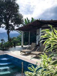 un patio avec deux chaises et une piscine dans l'établissement Casa com Piscina, Vista e Acesso ao Mar, à Angra dos Reis