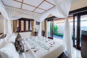 ein Schlafzimmer mit einem weißen Bett mit Blumen darauf in der Unterkunft The Maya Seminyak Villas in Seminyak