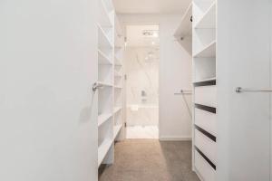 a bathroom with a walk in closet with white shelves at Opulent & Spacious Condo Overlooking Albert Park in Melbourne +37 photos