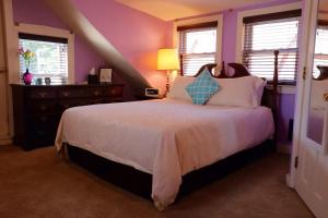 1 dormitorio con 1 cama con paredes y ventanas moradas en Stepping Stone Inn, en Salem