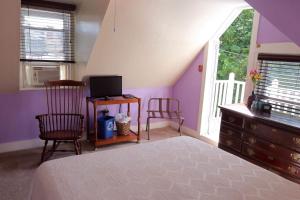 a bedroom with purple walls and a bed and a tv at Stepping Stone Inn in Salem