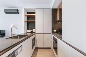 a kitchen with white cabinets and a sink at Sleek Lvl 75 Apt w Skyline Views in Aurora Complex in Melbourne