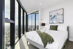 a bedroom with a white bed and large windows at Sleek Lvl 75 Apt w Skyline Views in Aurora Complex in Melbourne