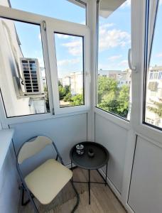 una silla y una mesa en una habitación con ventanas en Christal Apartment, en Bacău